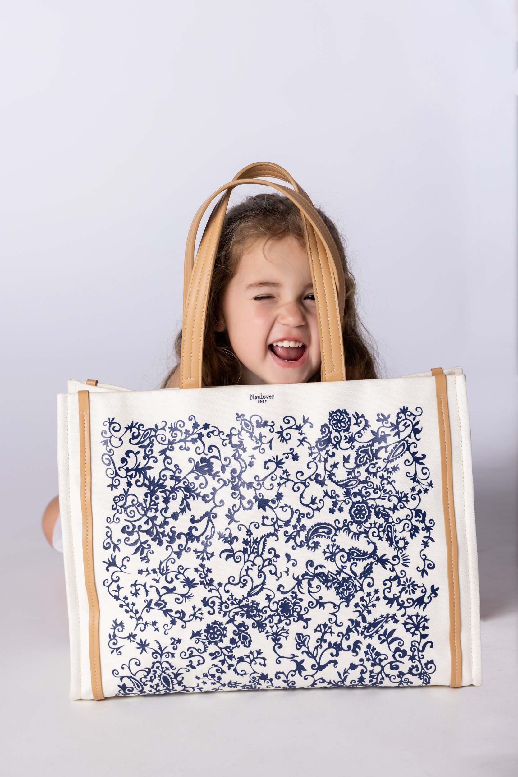 niña pequeña con bolso grande estampado blanco y azul