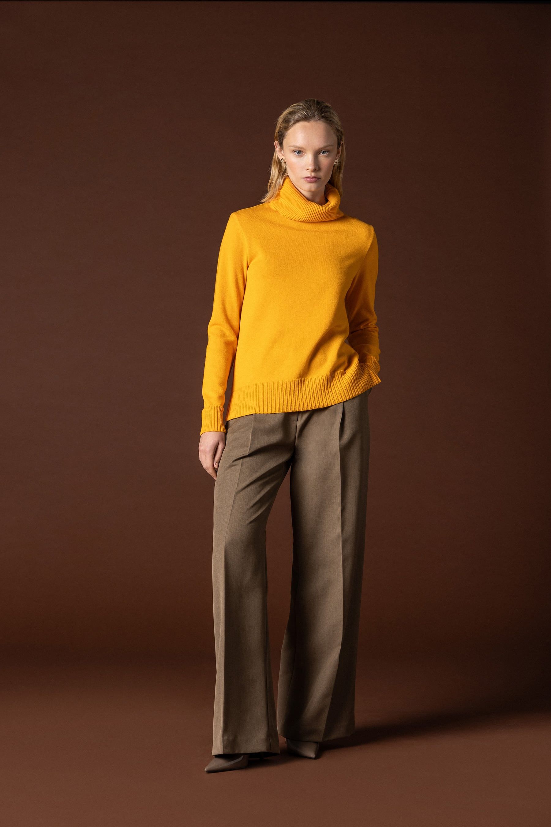 jersei cuello alto naranja con pantalon de traje beige