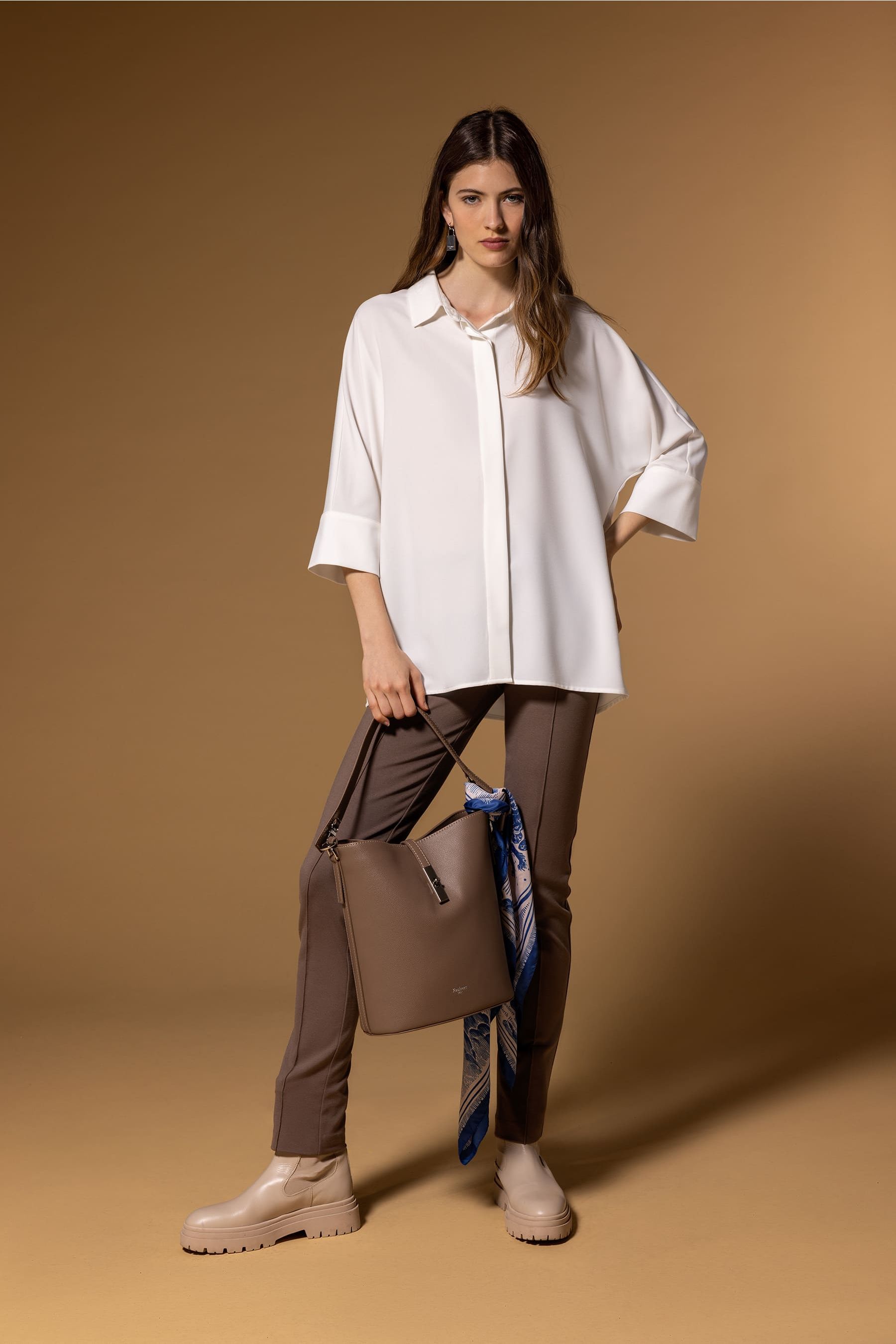 Look de mujer sofisticado y sencillo con blusa blanca y pantalones marrones