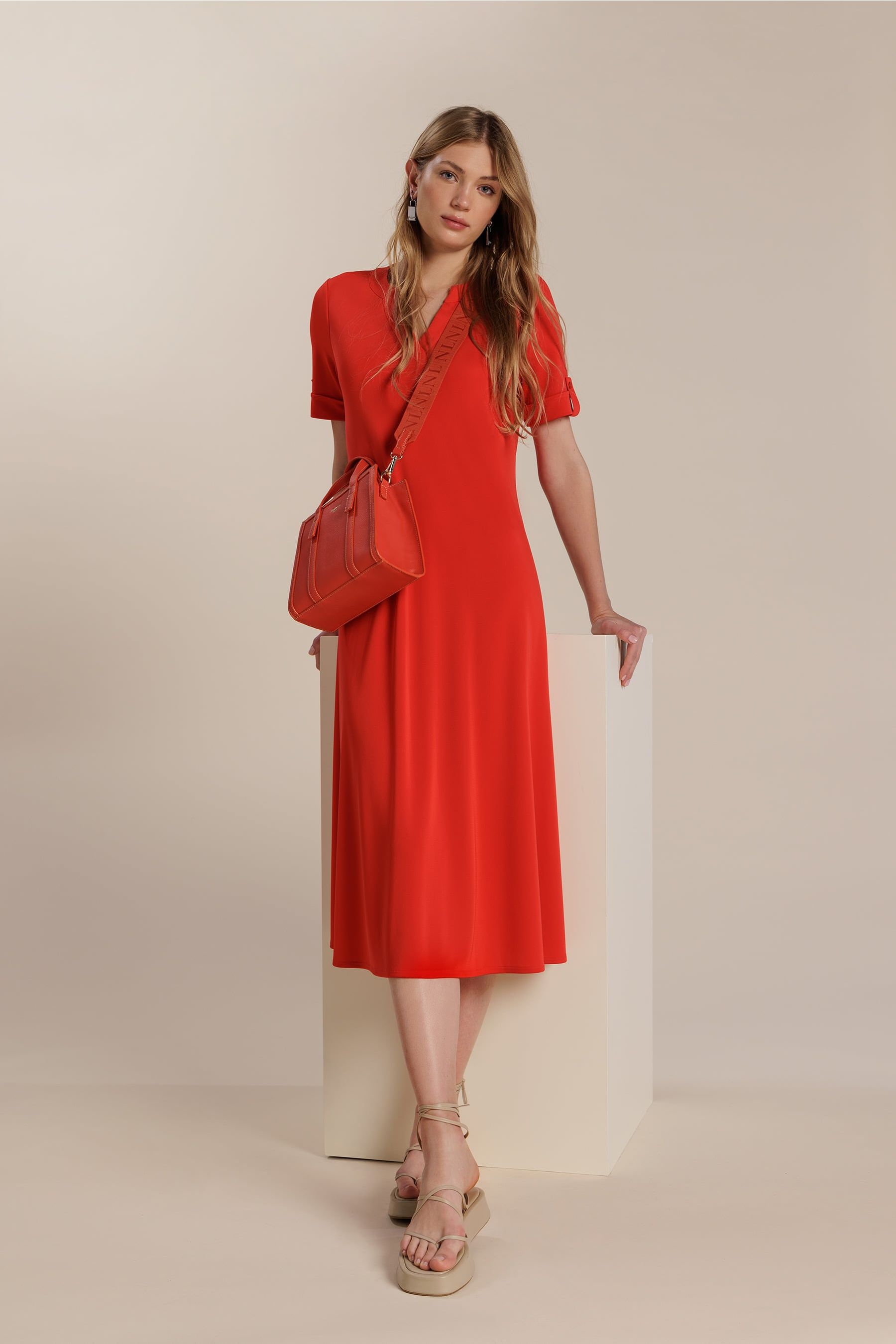 Mujer portando un vestido rojo de manga corta con un bolso a juego